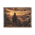 Woven blanket with a scenic design of a person standing in mountains at sunset.